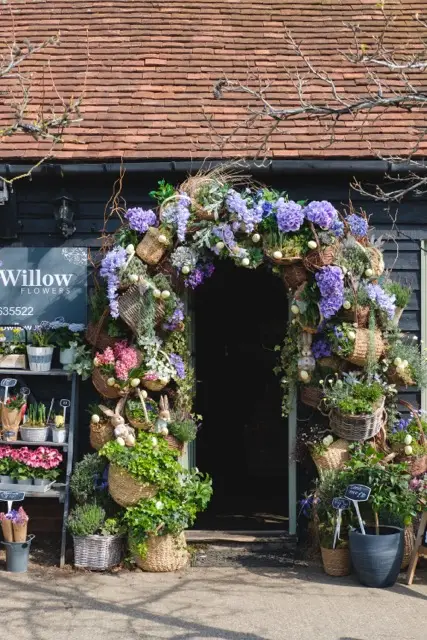Decorative flower and plant archway entrance to a shop with baskets and potted plants outside